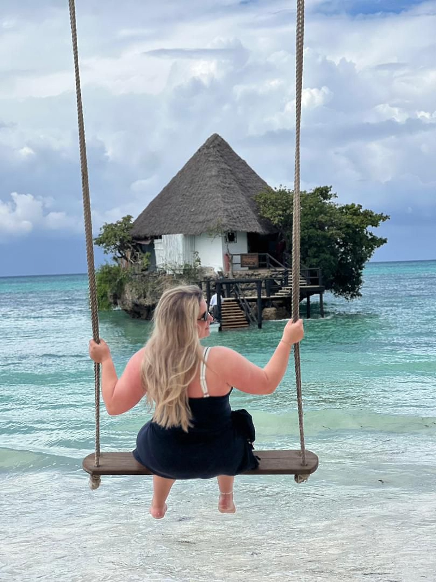 A traveller on a swing beside a Zanzibar island beach