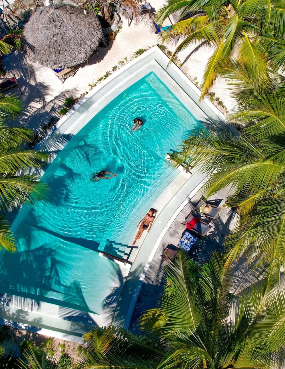 Aerial view of a palm-framed turquoise pool on the Zanzibar coast