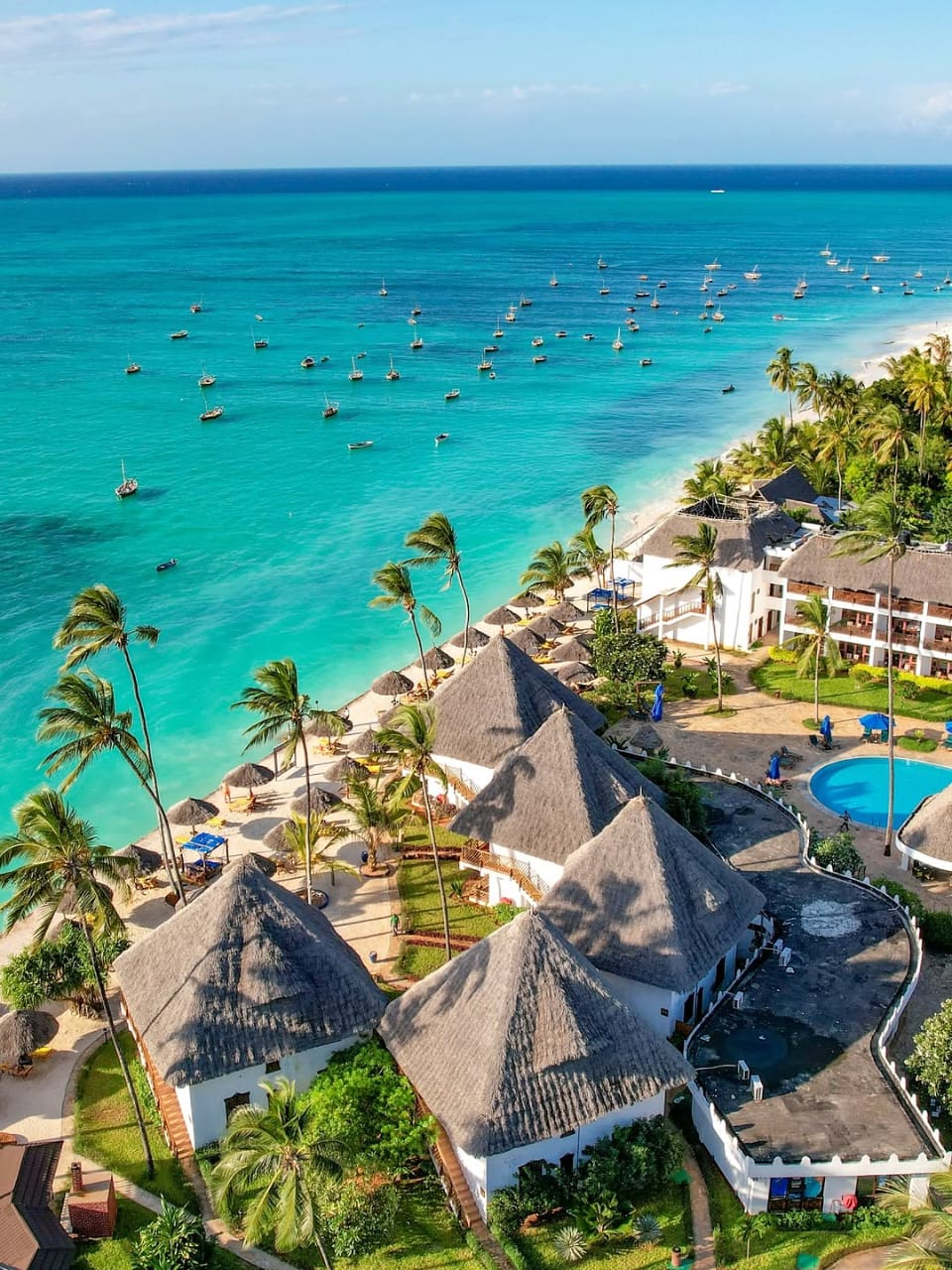 Aerial view of dhow boats, turquoise sea and a Zanzibar beach resort